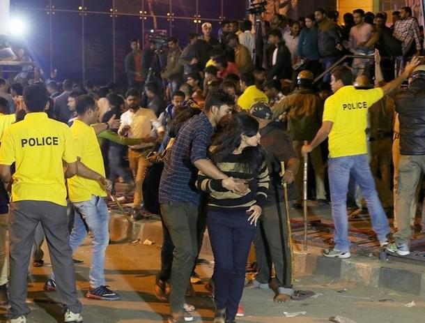 An Indian man helps a woman leave as police personnel try to manage crowds during New Year’s Eve celebrations in Bengaluru. (STR/AFP/Getty Images)